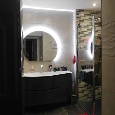 salle de bain rénovée avec des meubles modernes et design et un beau miroir lumineux